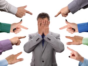 Hands pointing towards businessman holding head in hands concept