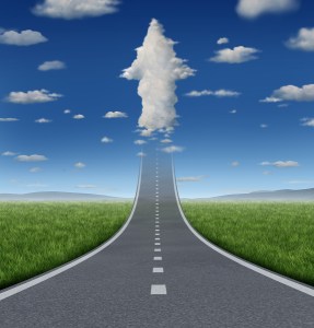 No limits success concept with a road or highway going forward fading into the sky with a group of clouds shaped as an upward arrow as a business symbol of financial freedom and aspirations.